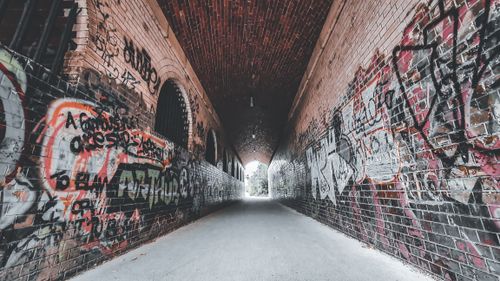 Free Empty arched shabby passage with graffiti on aged brick walls leading to green park in daytime Stock Photo