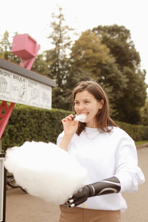 Woman Eating Cotton Candy on a Street