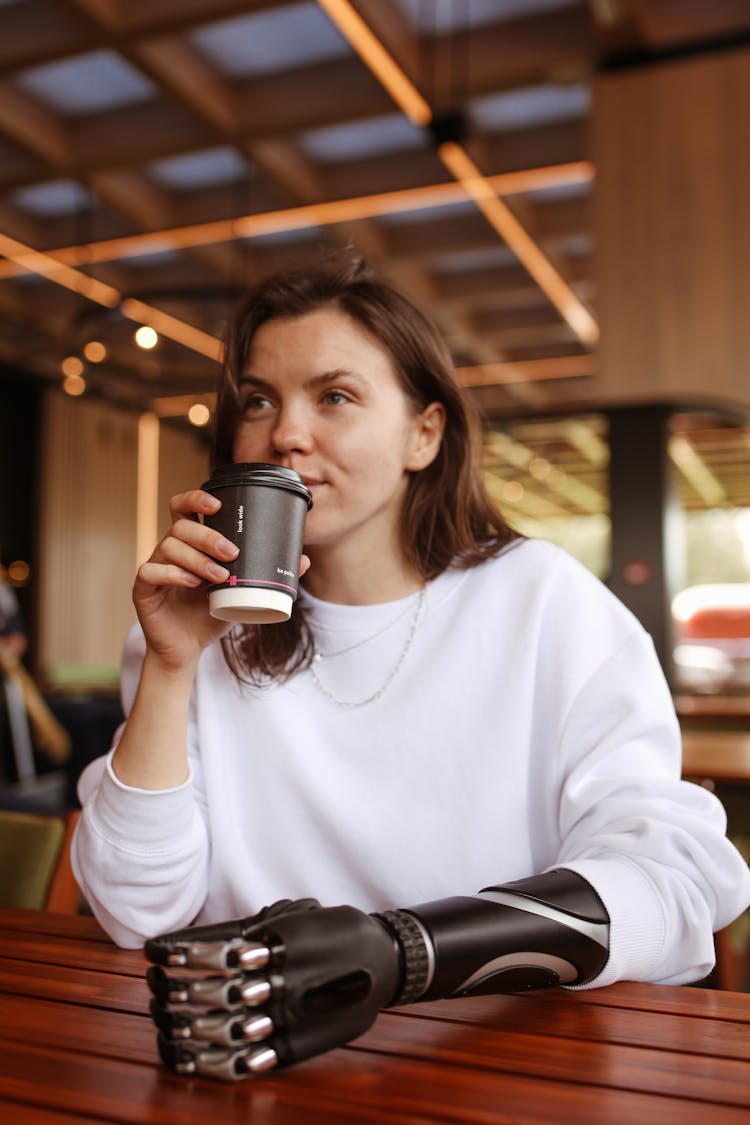 Woman With A Prosthetic Hand Holding A Paper Coffee Cup