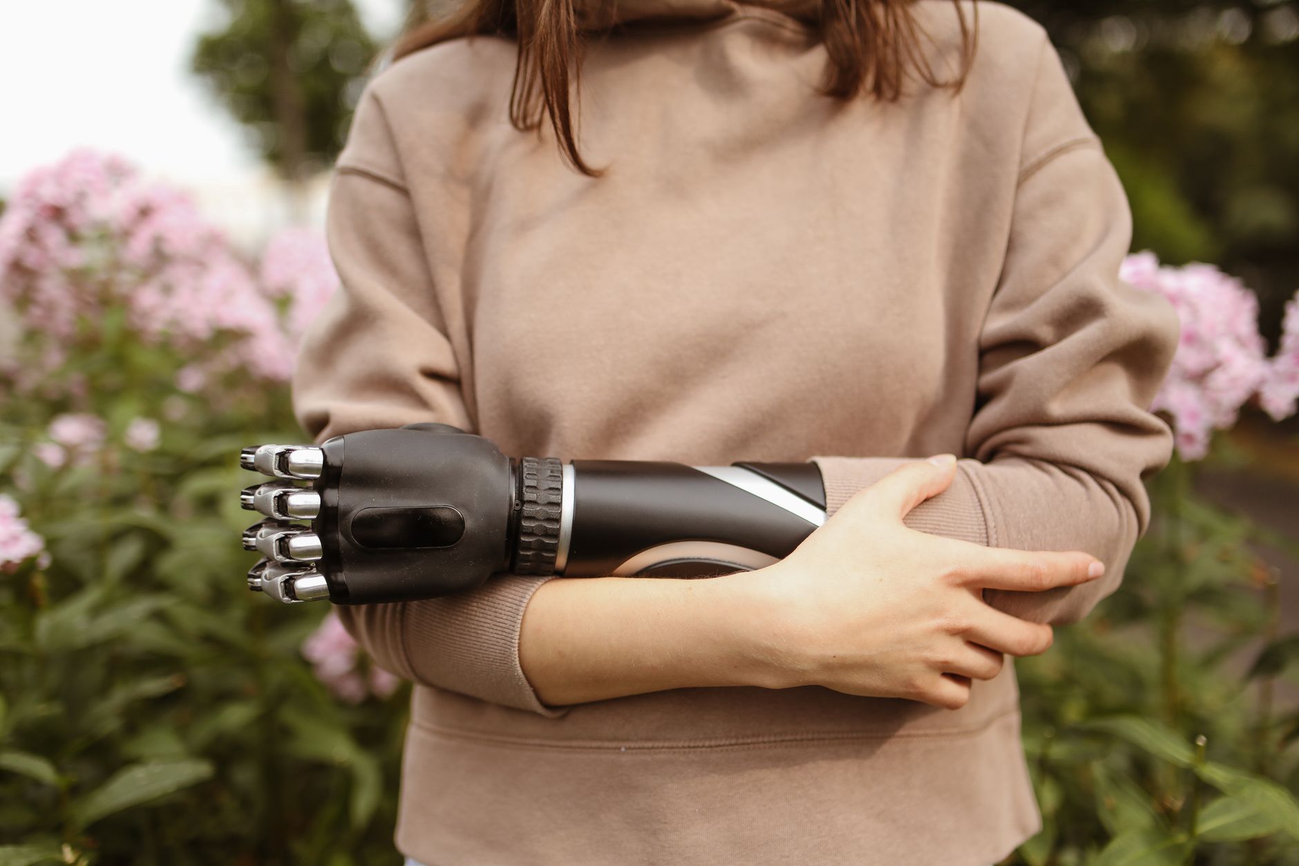 Close-up of a woman in a sweatshirt holding a prosthetic arm.