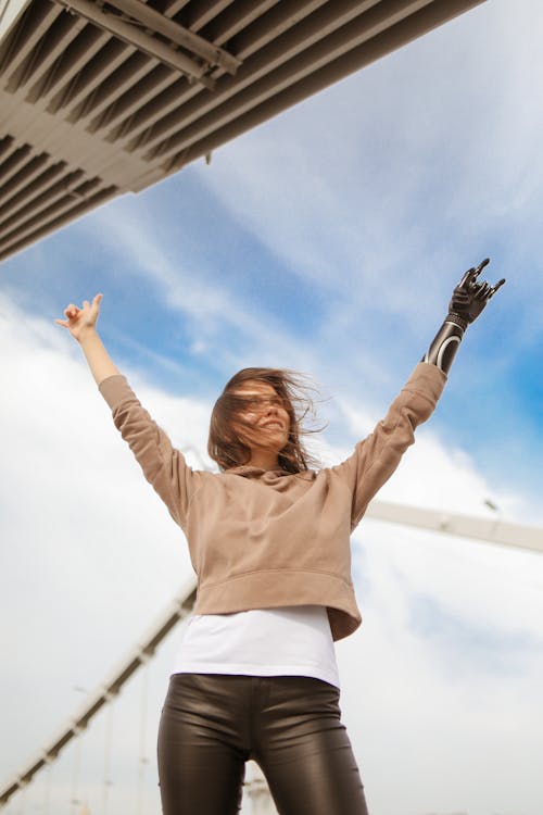 Woman in Brown Sweater Raising Her Arms