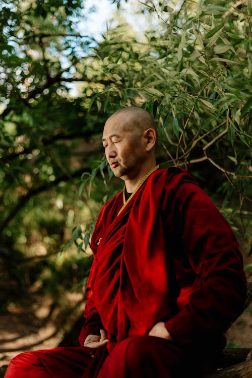 Man in Red Long Sleeve Dress Sitting while Eyes Closed