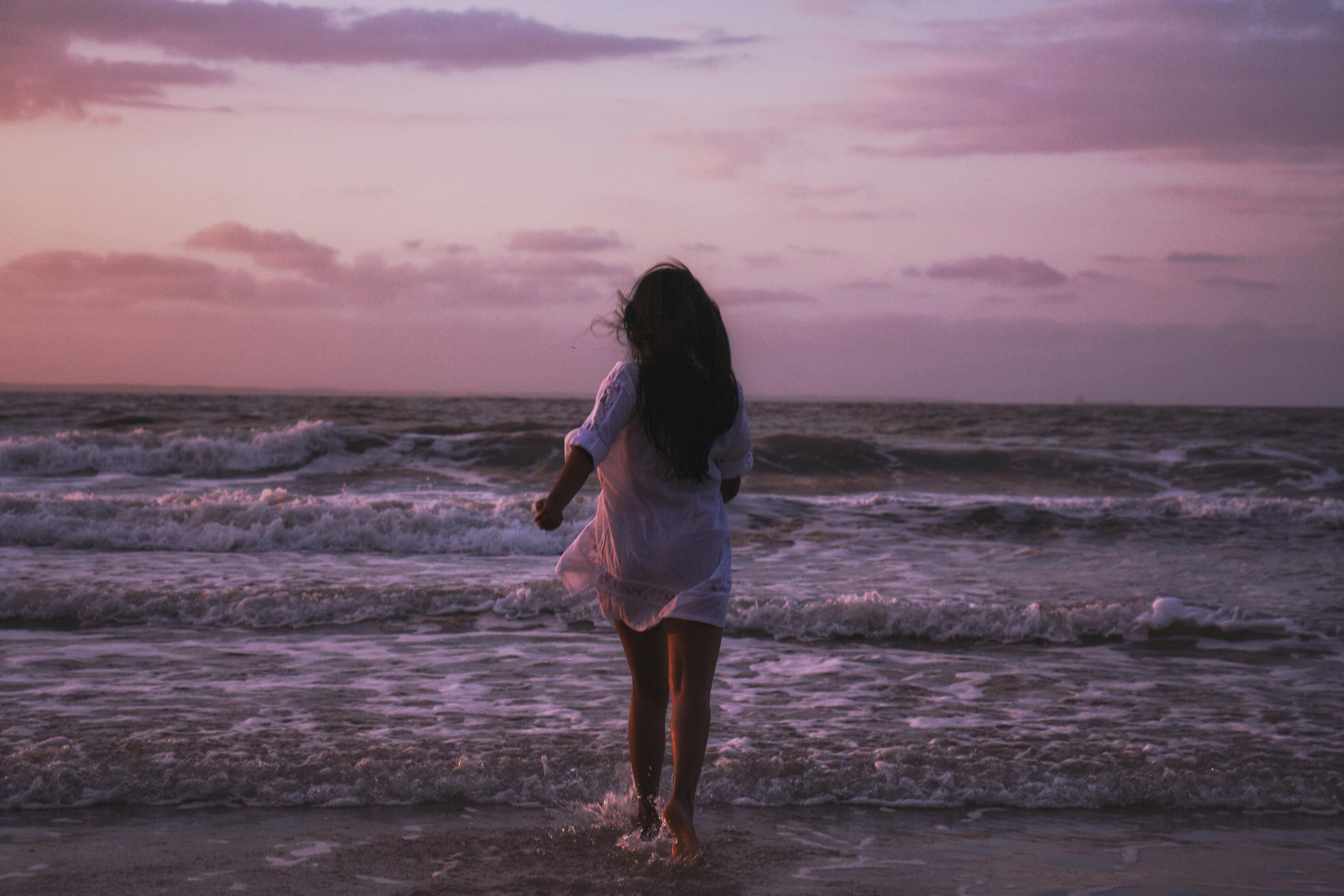 日落时分，一名女子走向大海，捕捉到海滩上宁静的时刻