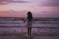 日落时分，一名女子走向大海，捕捉到海滩上宁静的时刻