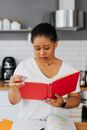 Woman Sitting Behind a Kitchen Counter and Reading a Book