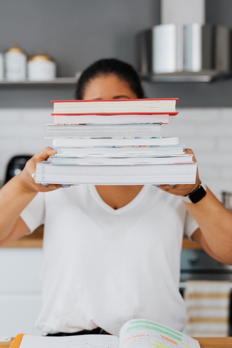 Woman Holding A Pile Of Books In Her Hands 