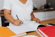 Woman in White Crew Neck T-shirt Writing on White Paper