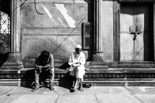Free Black and white street portrait capturing two men in deep thought against a textured wall. Stock Photo