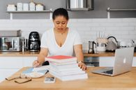Woman Sitting Behind a Kitchen Counter and Studying 