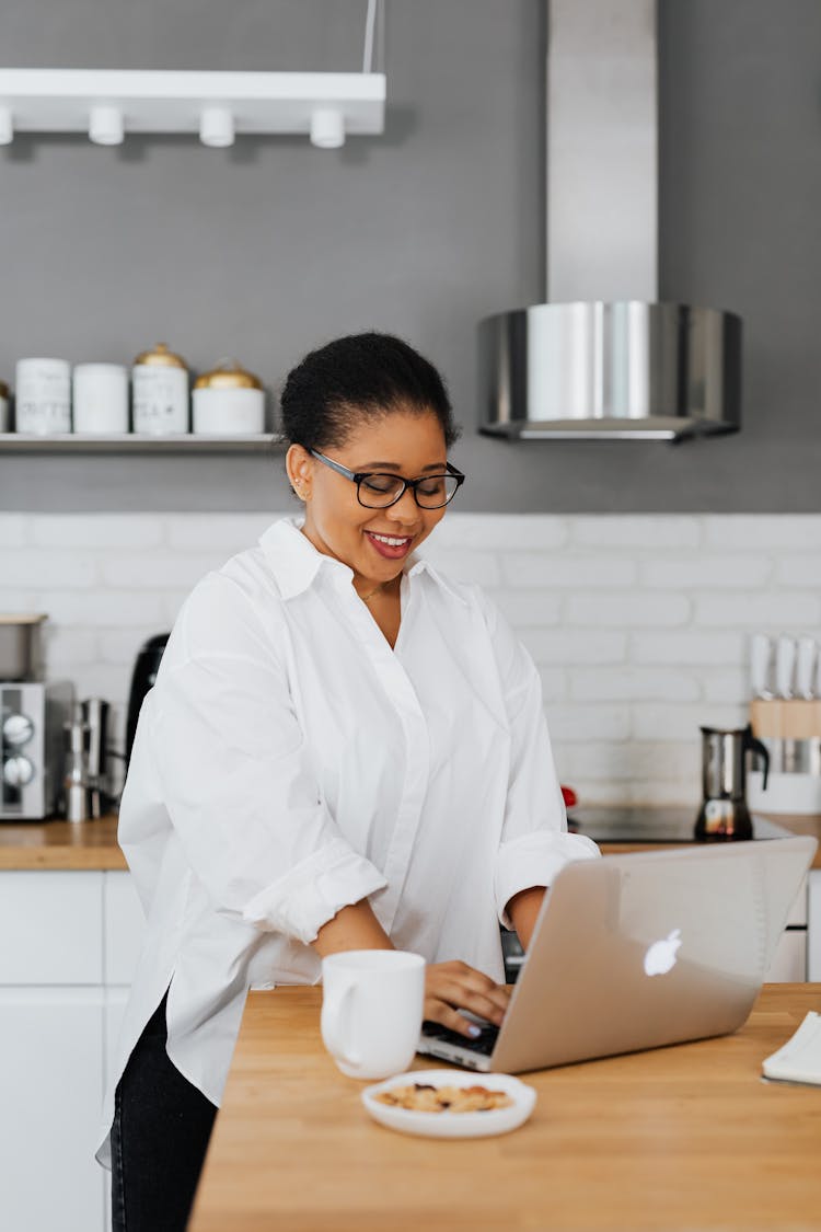 Woman Sitting Behind a Kitchen Counter And Using A Laptop 