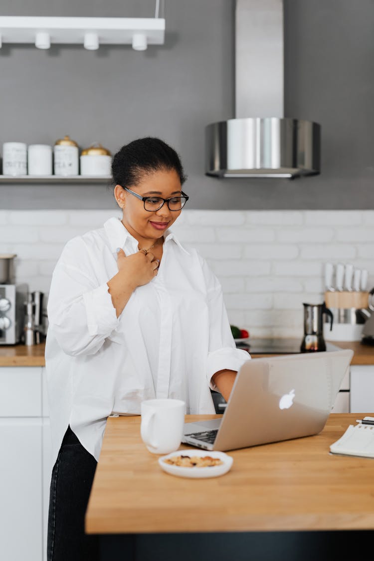 Woman Sitting Behind A Kitchen Counter And Using A Laptop 