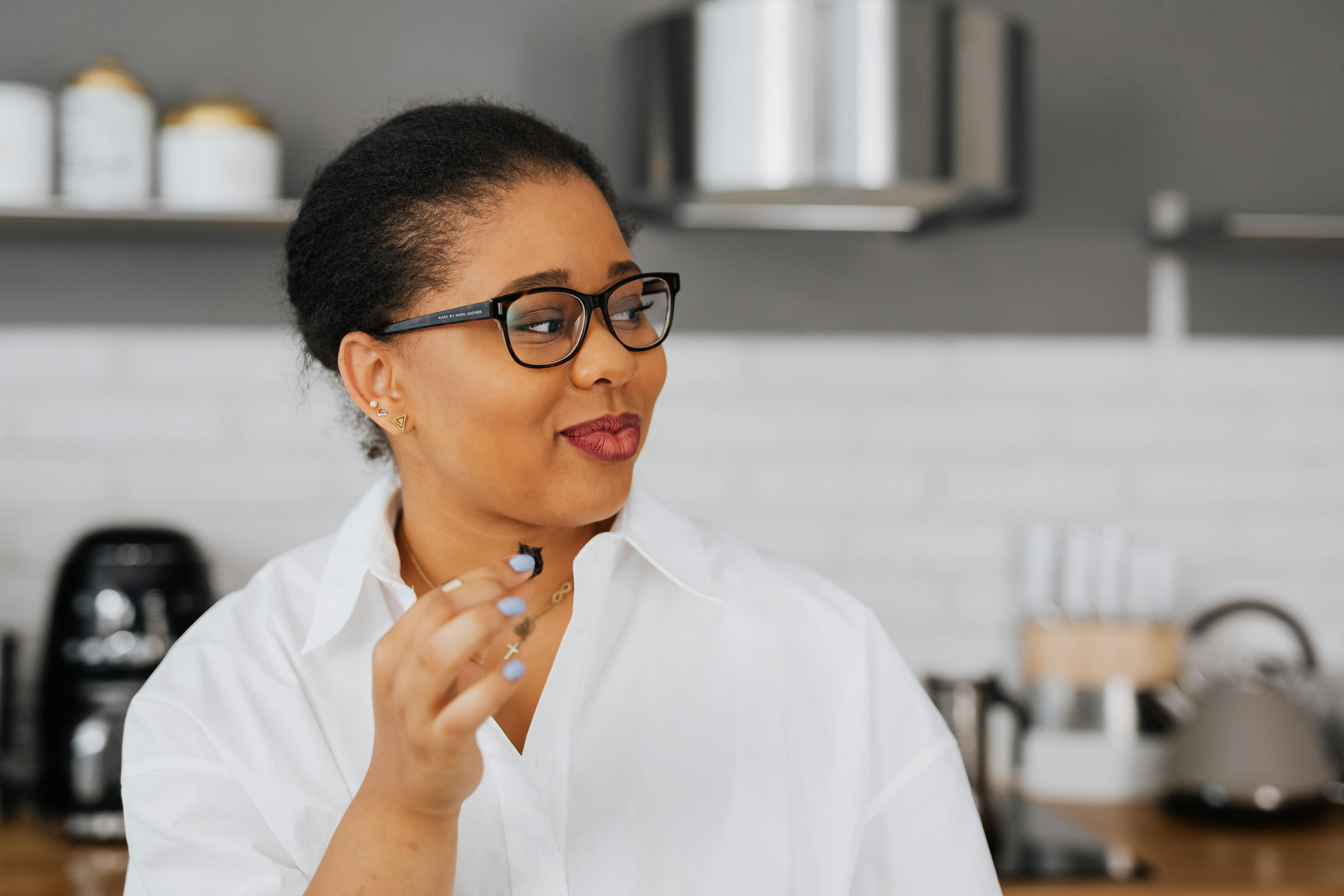 country style adult day care - Close-up of an adult woman with glasses in a modern kitchen, looking sideways with a smile.