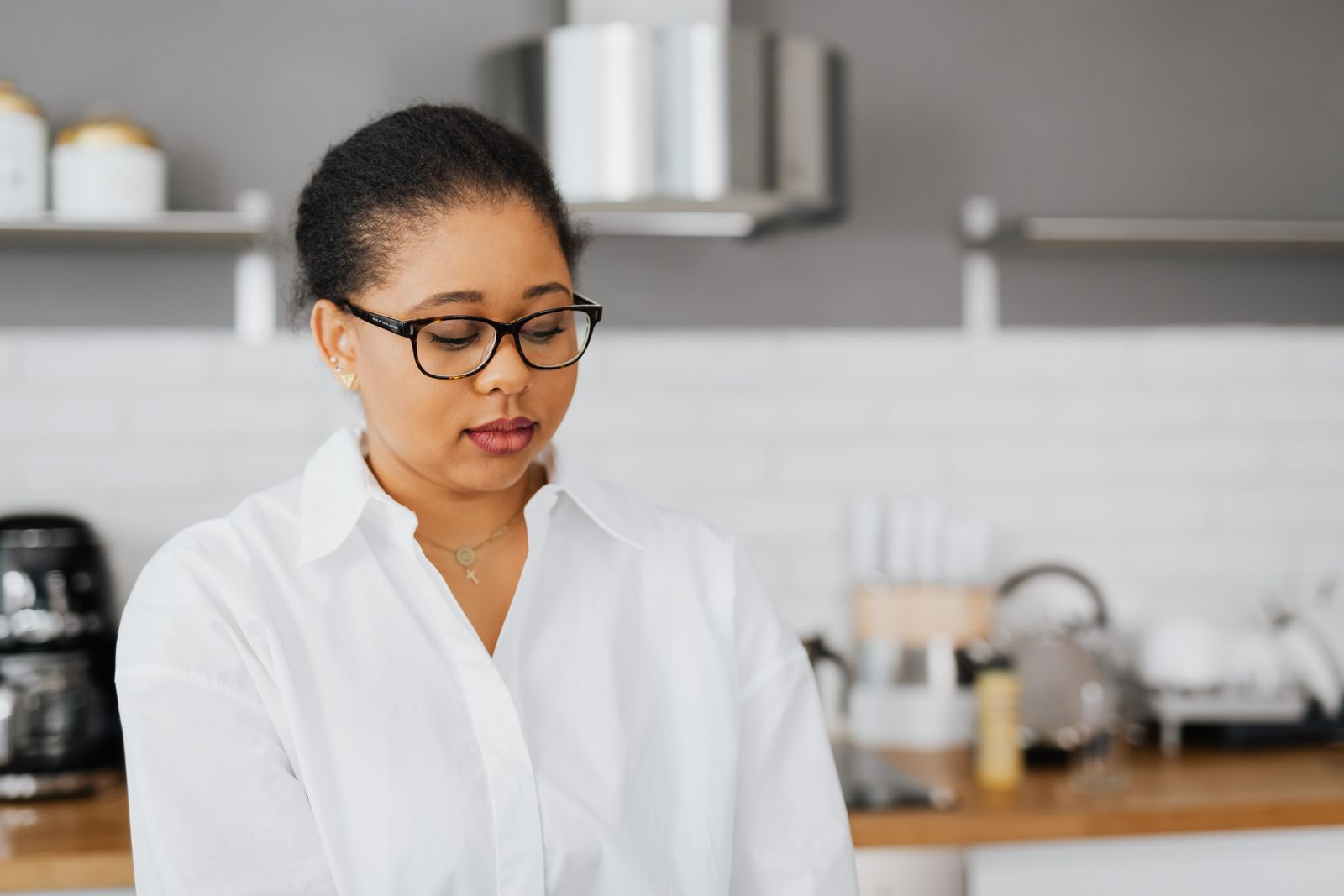 Woman in glasses standing in her kitchen