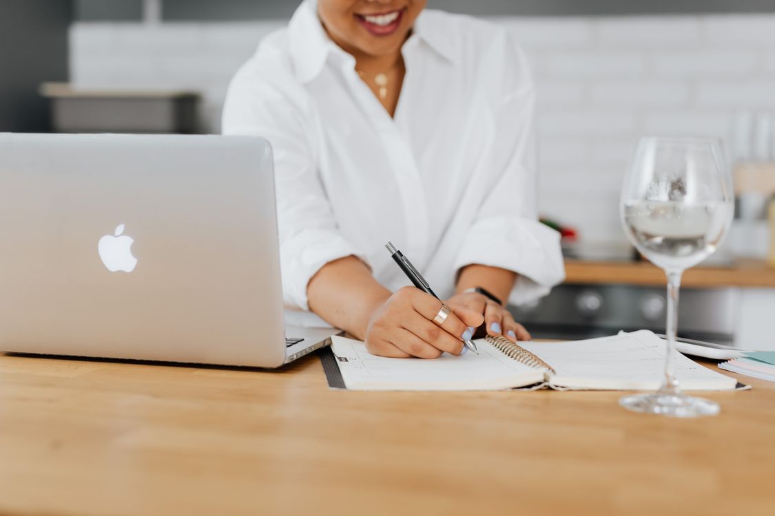 Person in White Top Writing on Notebook · Free Stock Photo