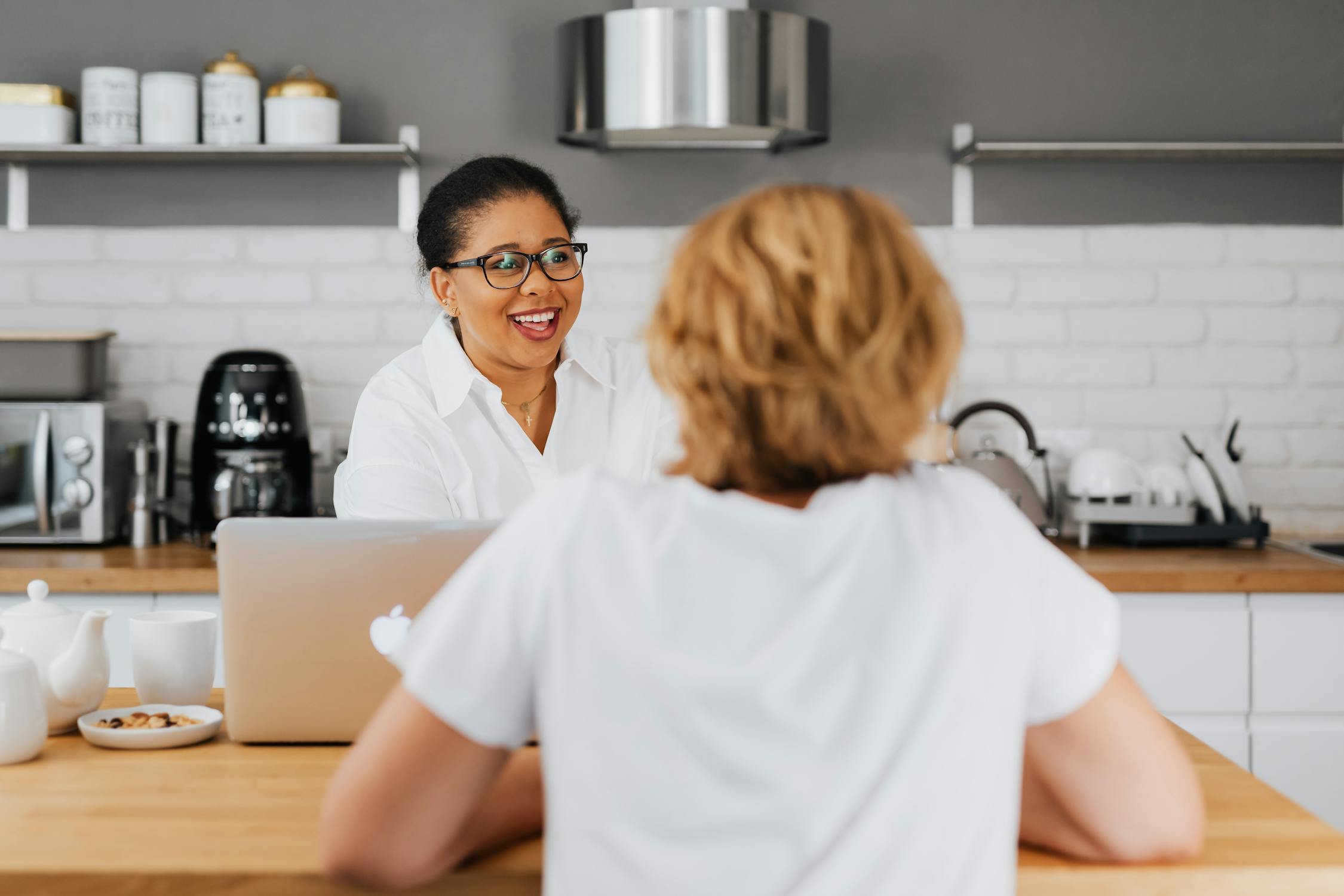 Woman in White Top Talking to Another Woman in the Kitchen