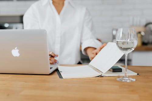 Free Person in White Top Flipping a Page in Notebook Stock Photo