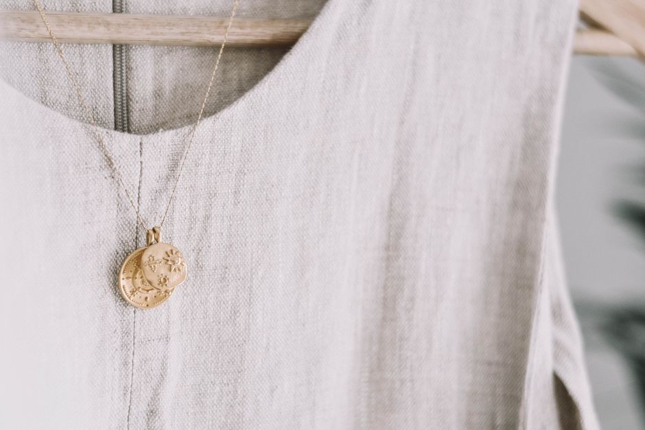 Close-up of a fine crescent moon pendant necklace in 14K gold on a neutral background, detailed jewelry photography