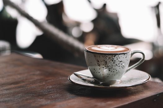 Close-up of a latte with beautiful art in a speckled cup in a cozy Bali café.