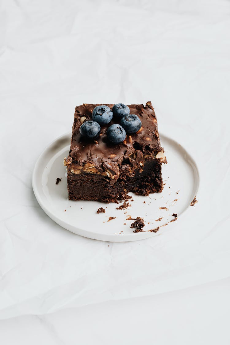 Chocolate Brownie With Blueberries On White Ceramic Plate