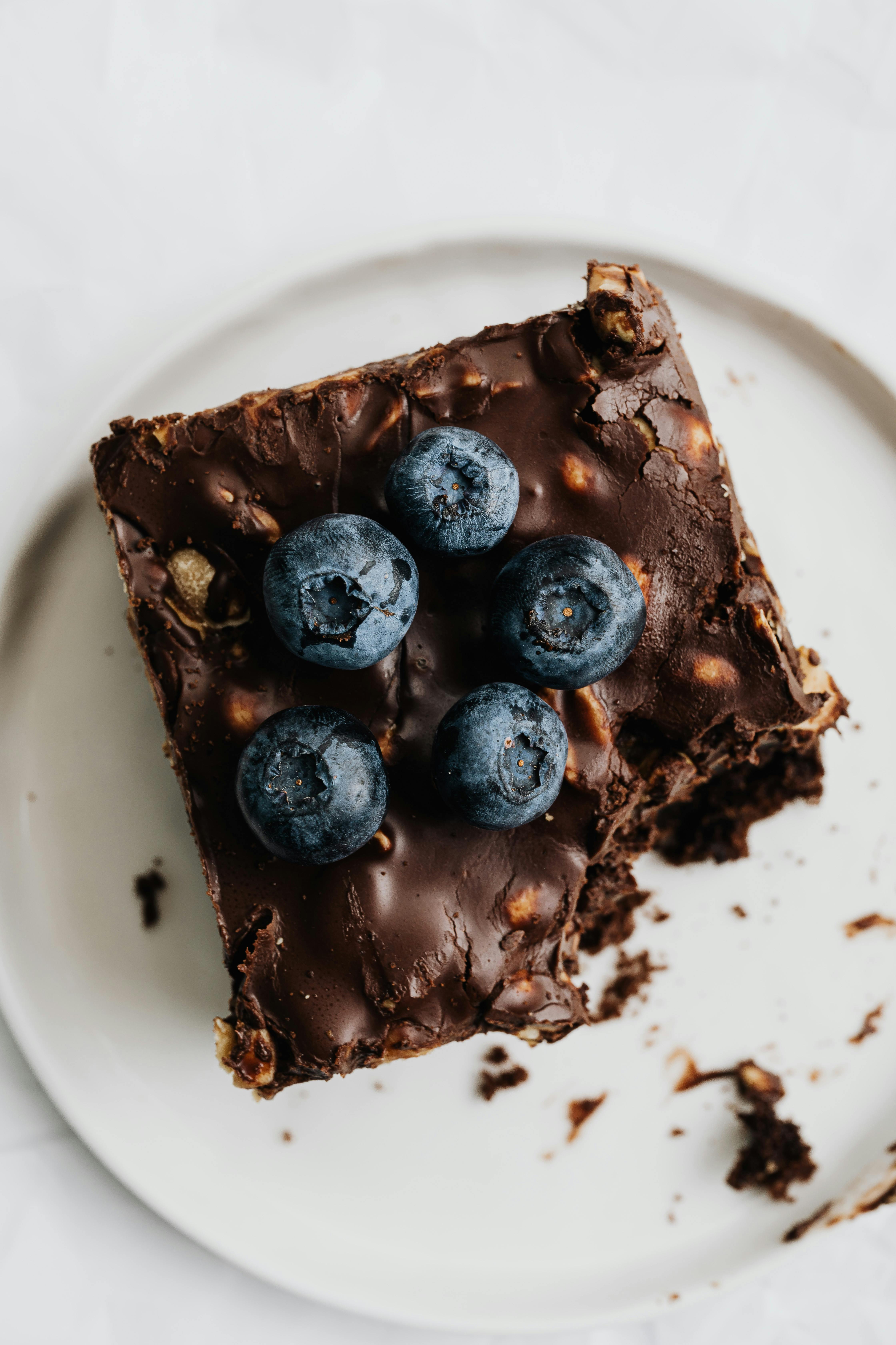 chocolate brownie with blueberries on white ceramic plate