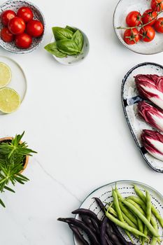 A vibrant composition of fresh vegetables and herbs on a clean white surface, perfect for healthy eating themes.