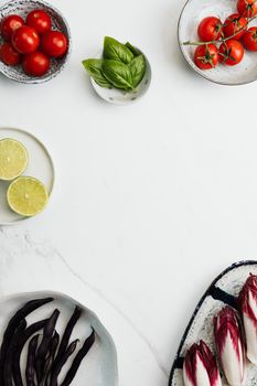 Top view of fresh vegetables and herbs arranged on a marble surface, ideal for cooking inspiration.
