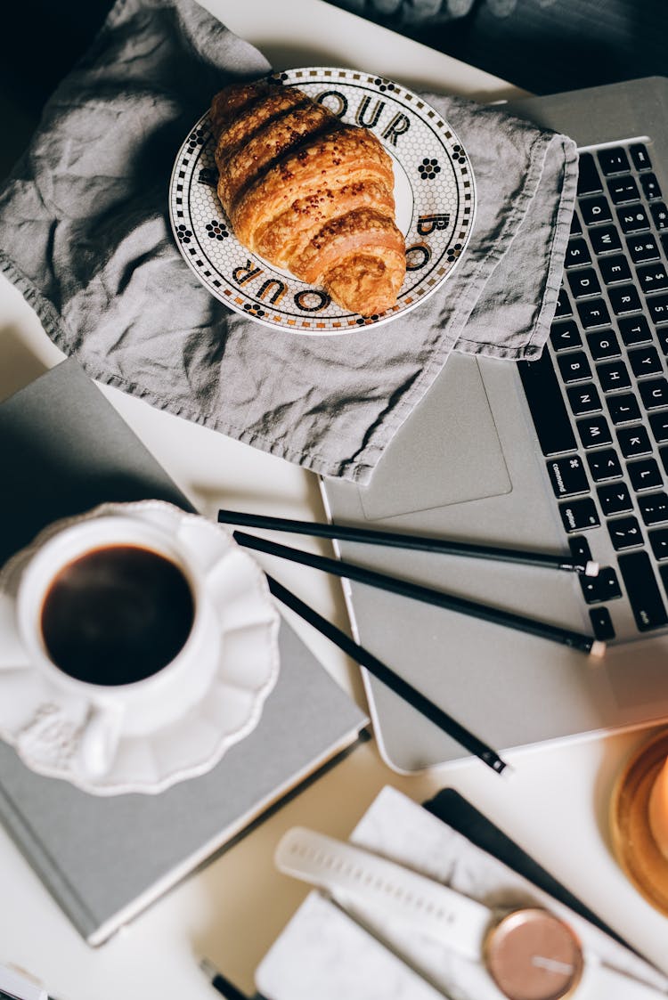 A Cup Of Coffee And Croissant Bread On A Table