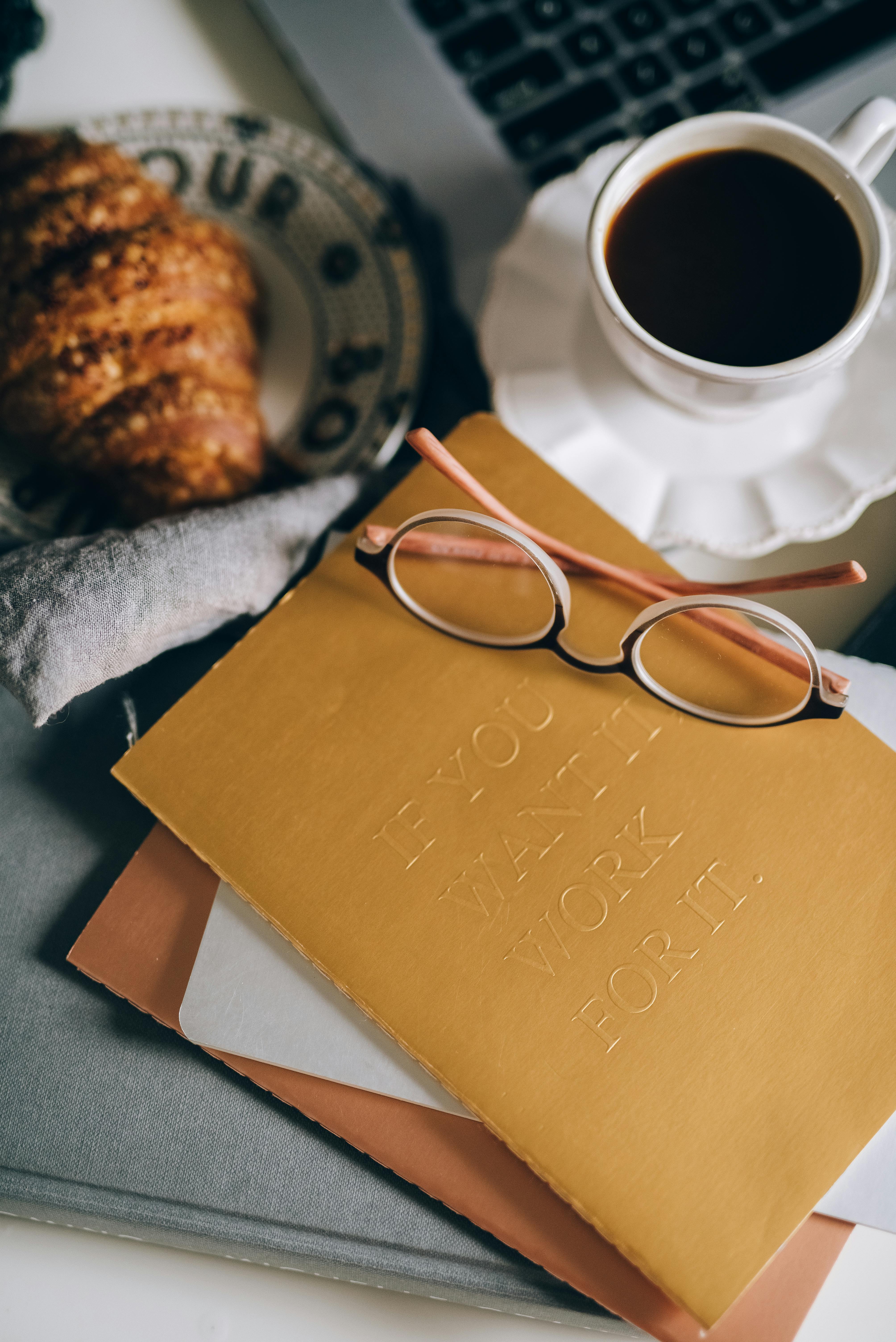 舒适的工作空间配有黑咖啡、羊角面包和笔记本，助您开启高效早晨