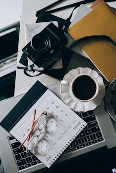 Flat lay of a modern workspace with camera, coffee, and calendar for creative inspiration.