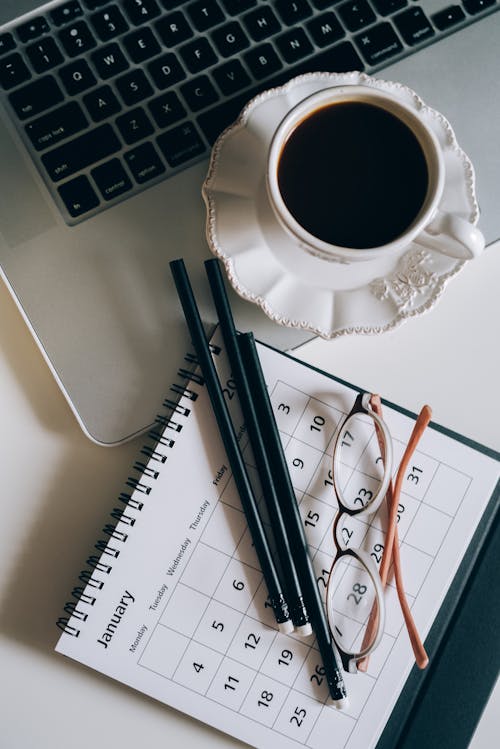 Cup of Black Coffee Beside a Calendar