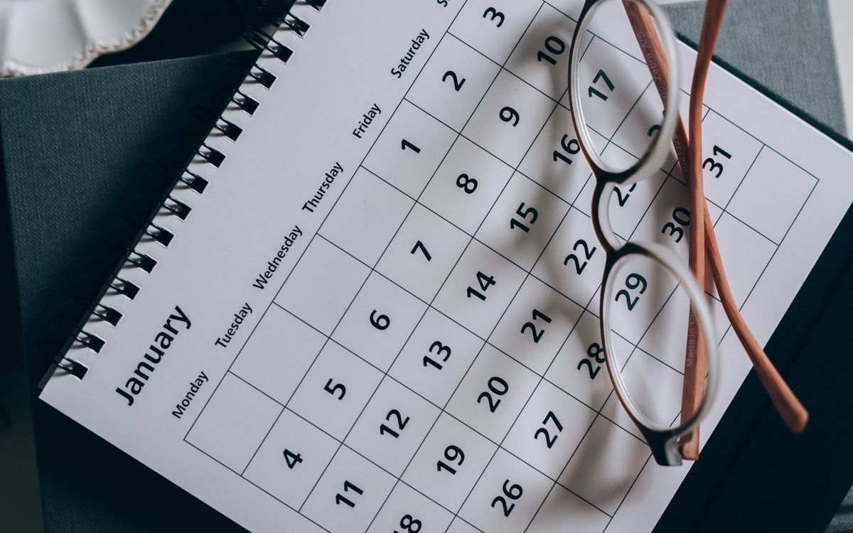 A close-up of a January calendar with eyeglasses on a table, emphasizing planning and organization.