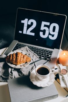 A cozy workspace setup with a laptop, coffee, and croissant, perfect for relaxed productivity.