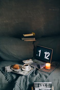 A cozy evening scene with a laptop, coffee, and candlelight creating a warm ambiance.