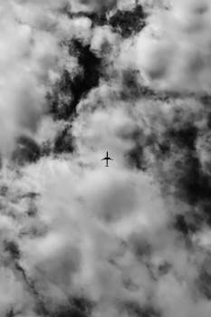 Black-and-white image of an airplane silhouette among dramatic clouds, capturing aviation in a grayscale tone.