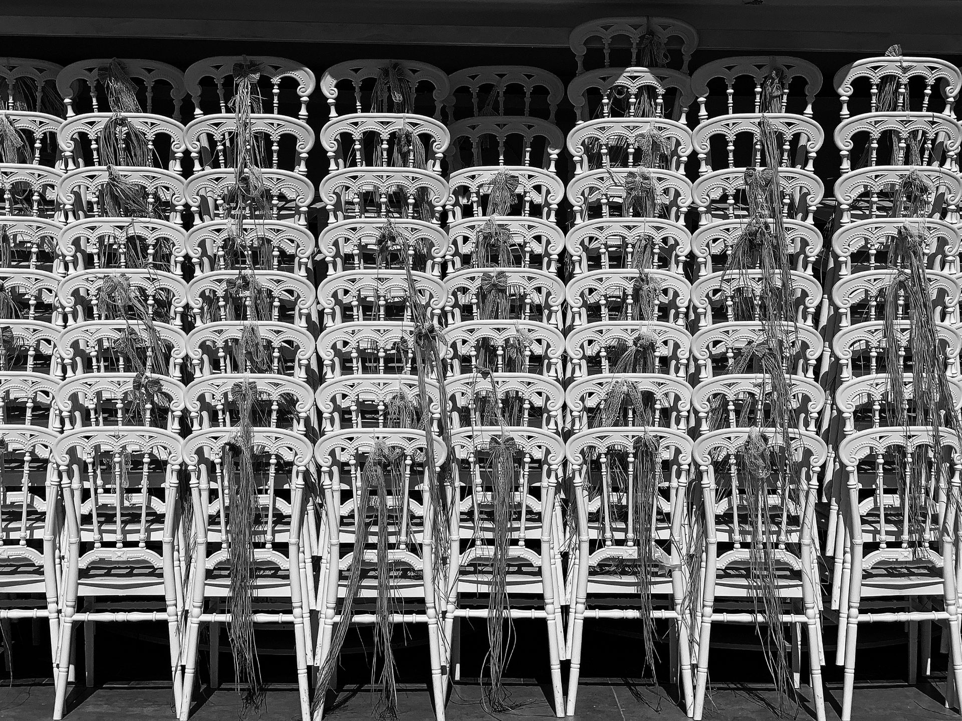 Artistic black and white photo of stacked vintage chairs with intricate patterns.