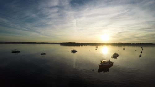 Free Peaceful boats floating at sunrise over calm seas, creating a tranquil scene perfect for meditation. Stock Photo