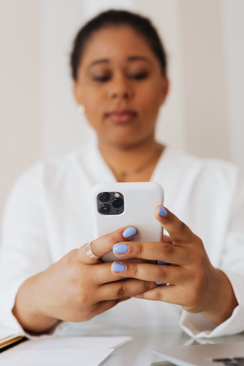 Woman in White Top Holding a Cellphone