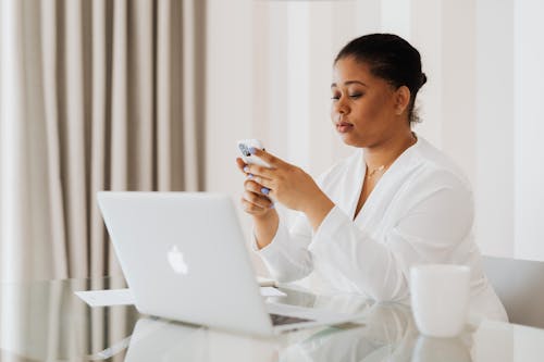 Free Woman in White Top Sitting while Using Cellphone Stock Photo