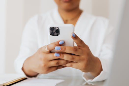 Close-up of a person using a smartphone with pastel nails, showcasing modern technology indoors.