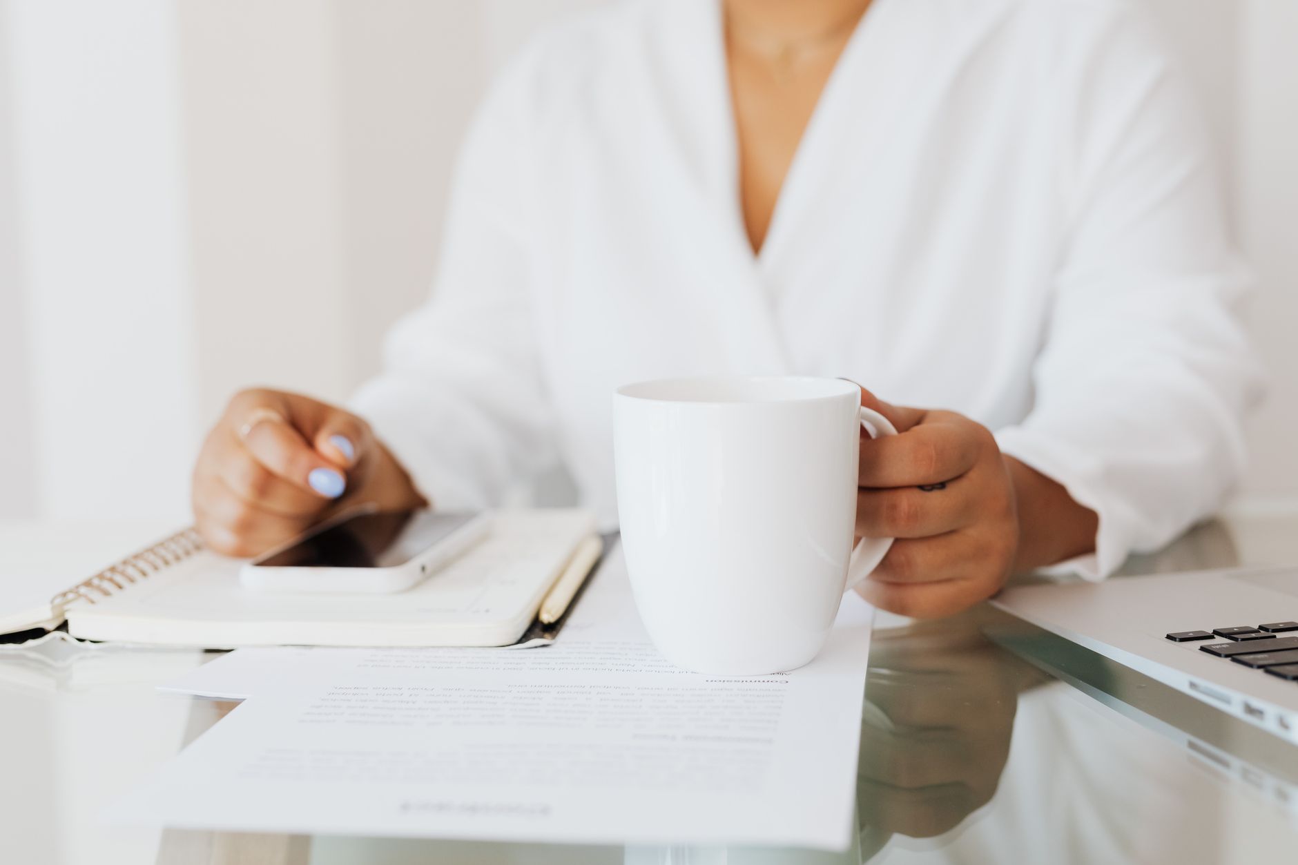 A coach at a desk reading a printed document beside a notebook and a cup of coffee