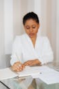 一位穿着白色衣服的黑人妇女正在室内专注地写笔记