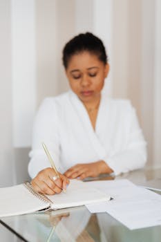 一位穿着白色衣服的黑人妇女正在室内专注地写笔记