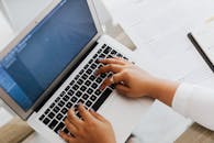 特写镜头展示了现代工作设置：双手在笔记本电脑上打字