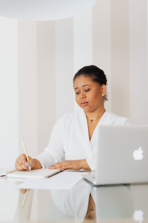 Woman in White Top Writing on Notebook