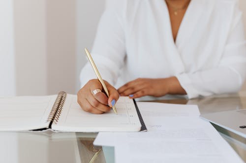 Free Person in White Top Writing on Notebook Stock Photo