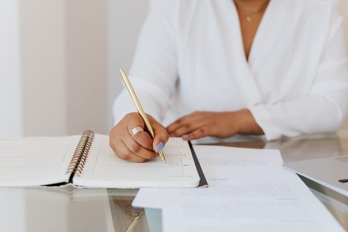 Free Close-up of a person writing notes in a planner with a gold pen, emphasizing organization. Stock Photo