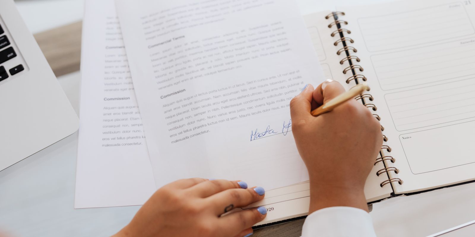 A person signing a contract document at a desk