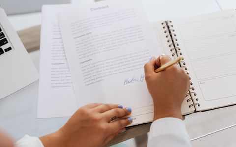 A person signing a contract document at a desk