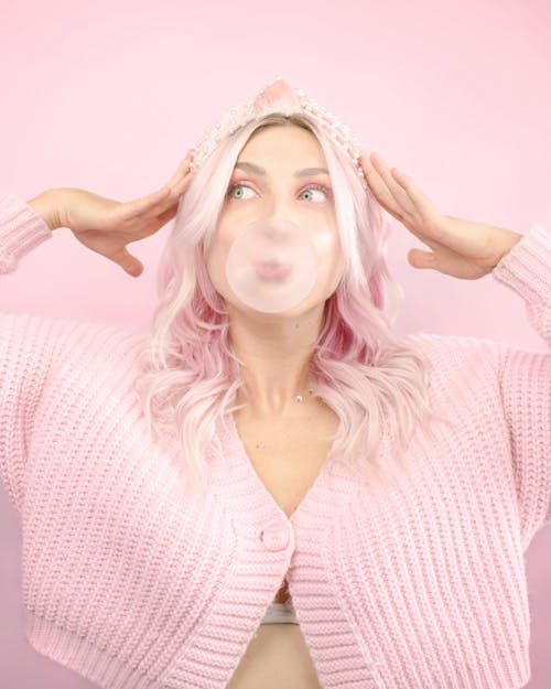 Woman in Pink Cardigan Blowing Bubble Gum