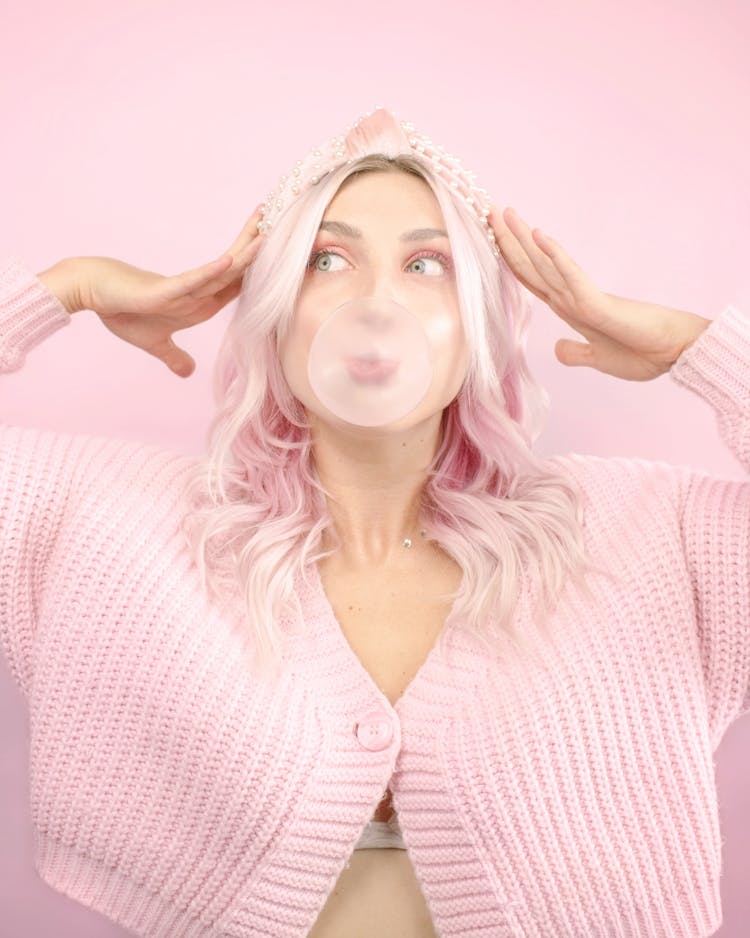 Woman In Pink Cardigan Blowing Bubble Gum